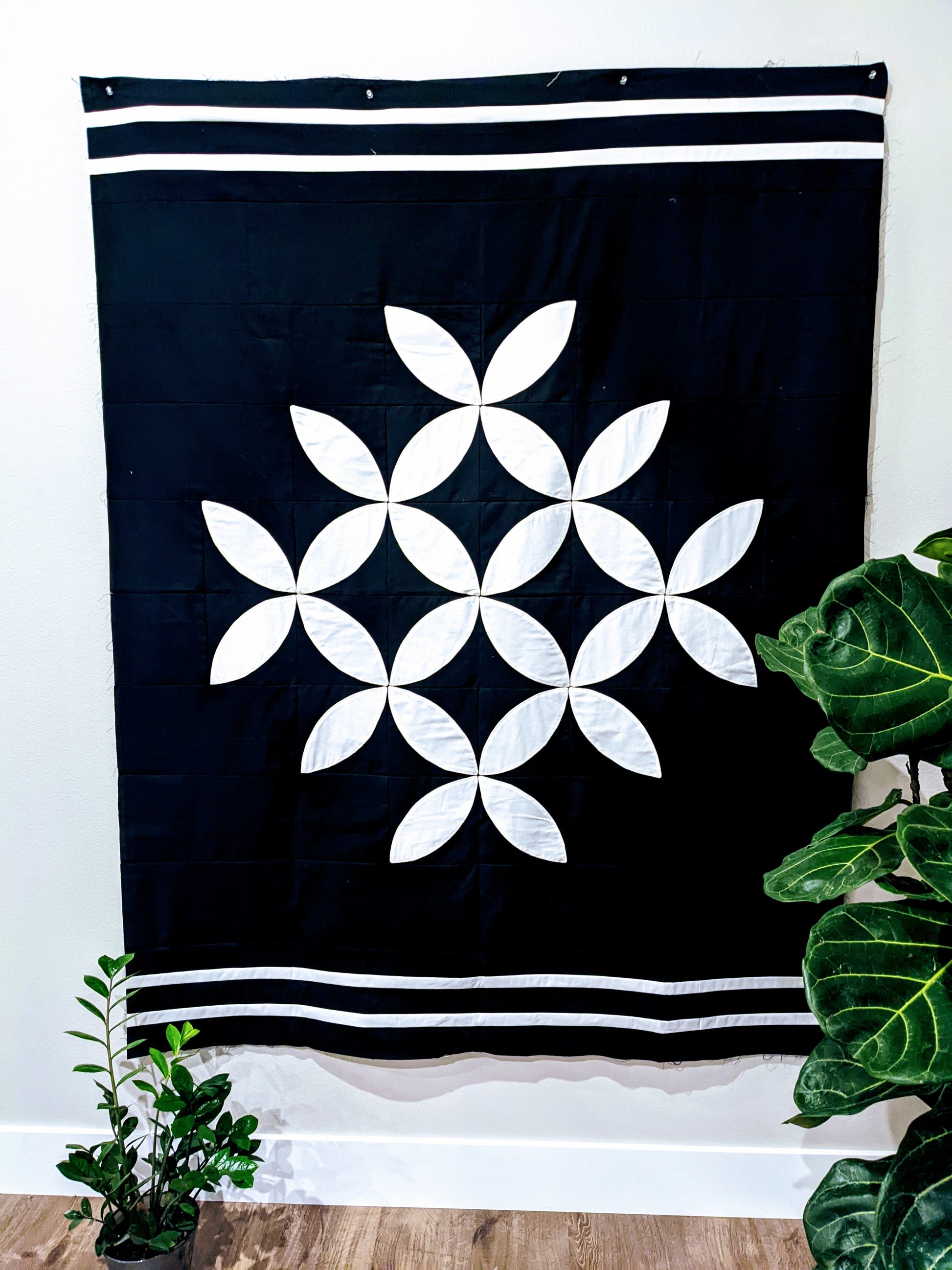 Black and white modern orange peel appliqué quilt on wall.