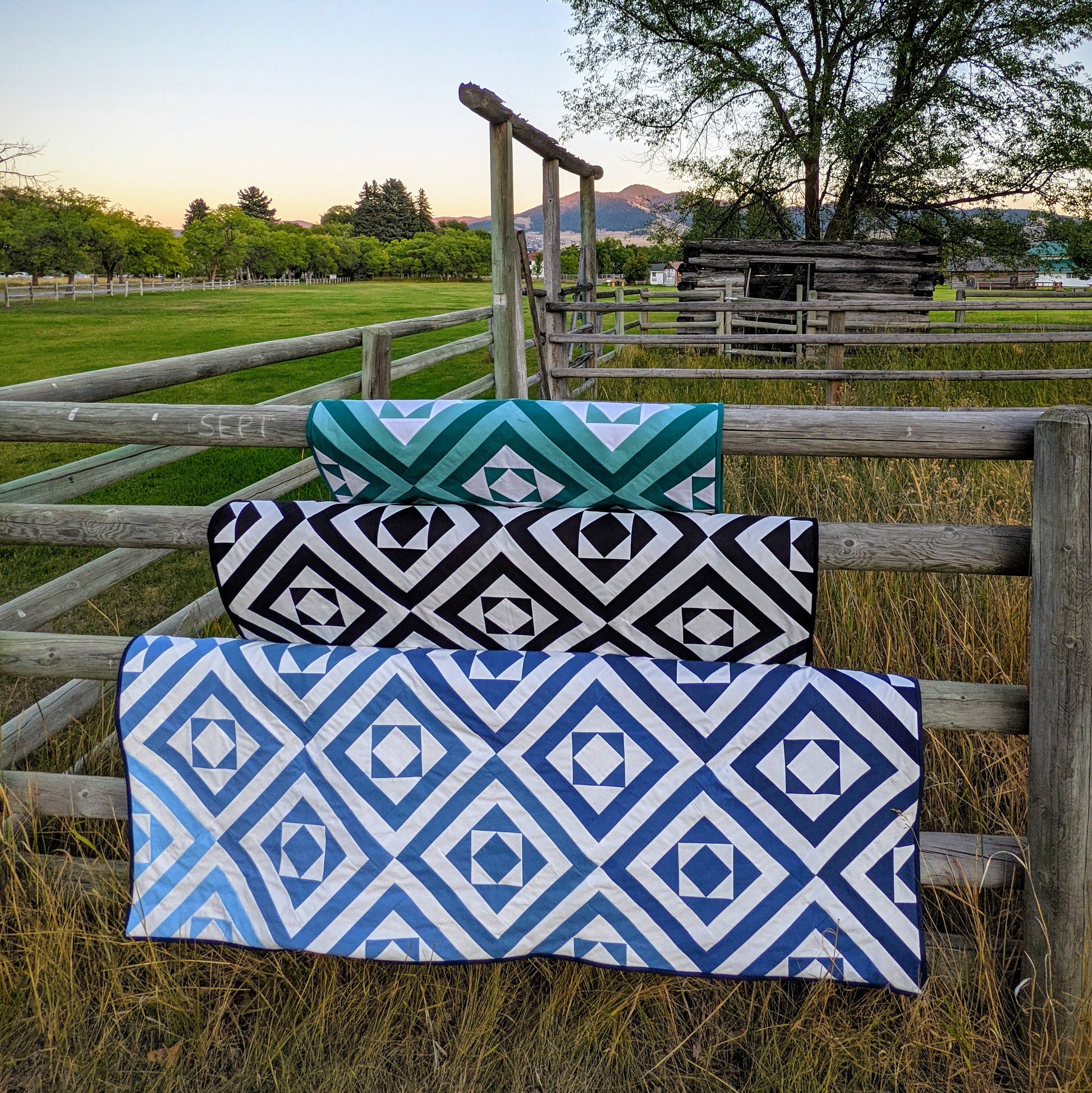 Three quilts on a fence.