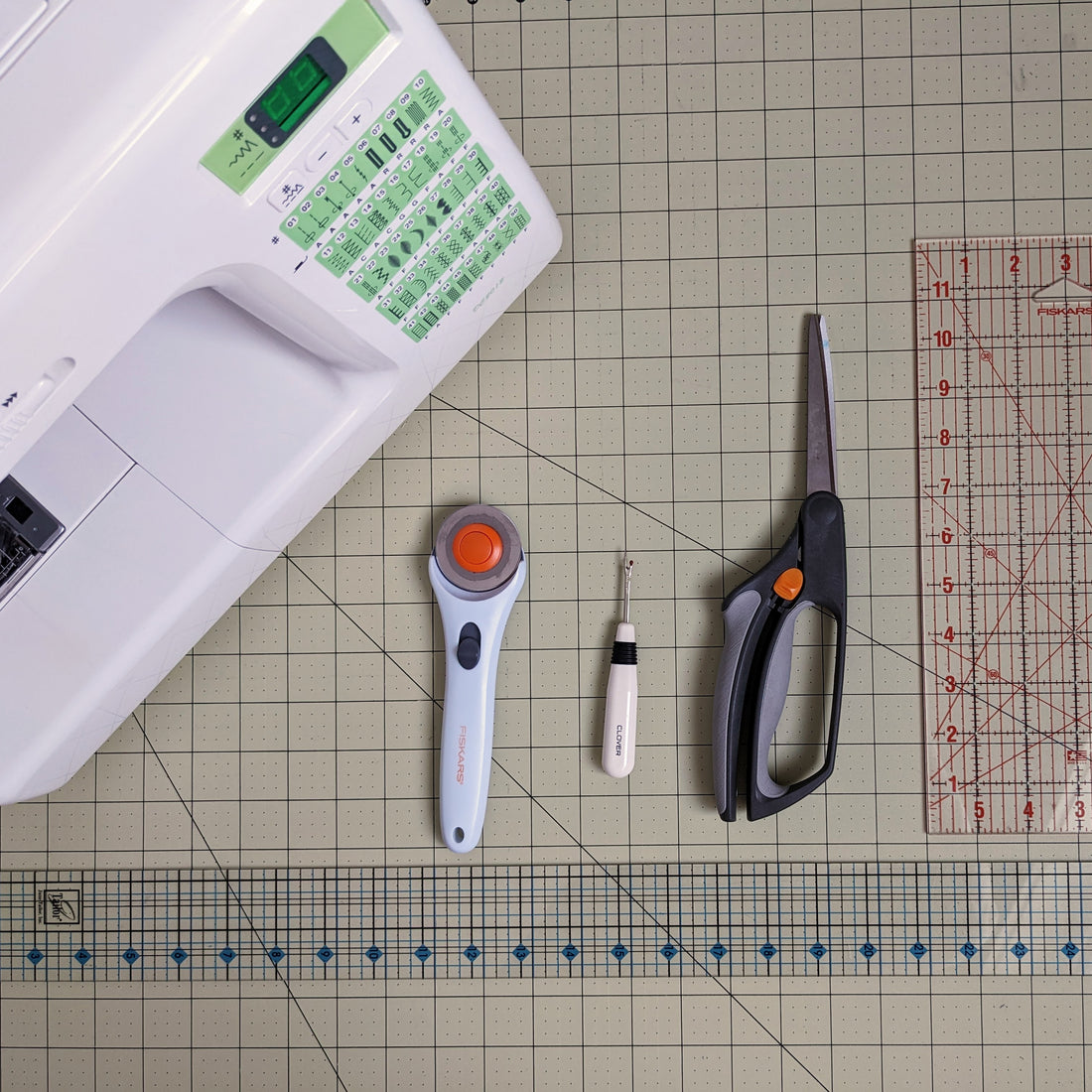 Essential quilt tools. sewing machine, rotary cutter, scissors, seam ripper and rulers