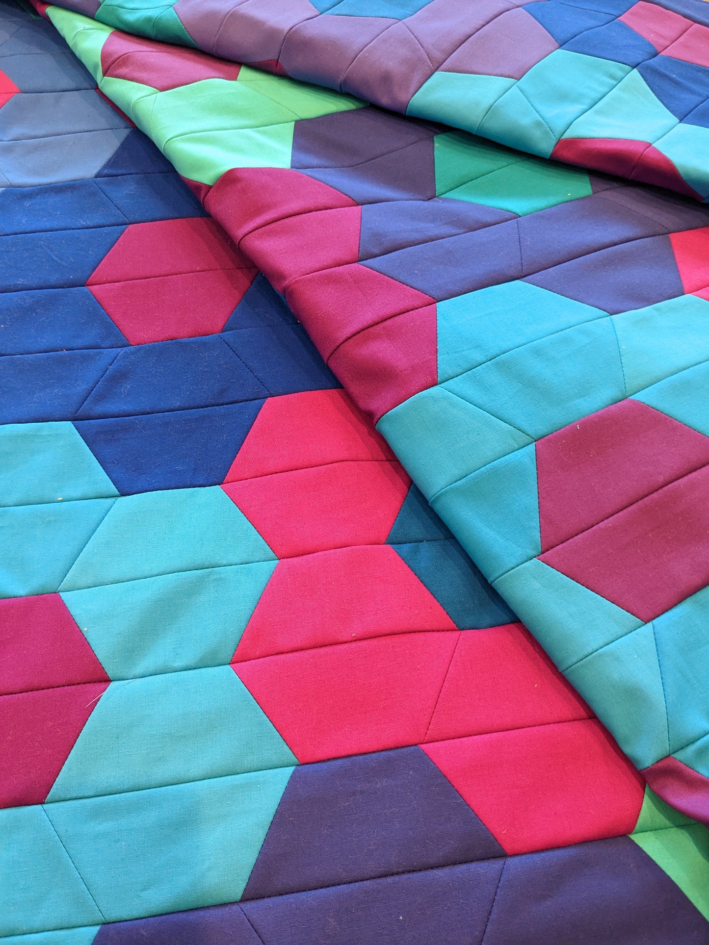 quilt with blue, purple and pink hexagon flowers folded