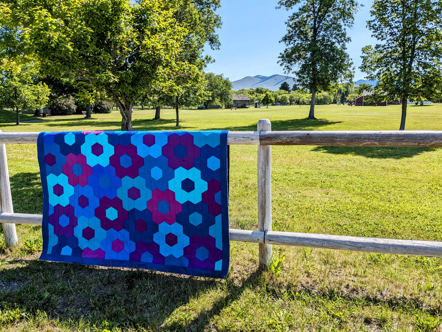 blue, purple and pink hexagon flower quilt on fence