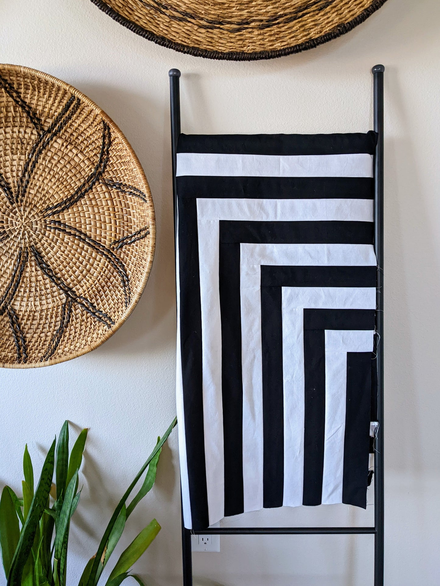 Black and white modern minimal quilt with straight lines on ladder with modern decor.